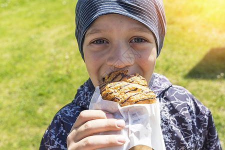 一个开心快乐的男孩 正在街上吃面包食物营养乐趣小吃享受包子烘烤垃圾甜食阳光图片