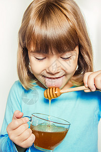 孩子吃蜂蜜 选择性的焦点 大自然水果治疗午餐微笑孩子们宏观港口婴儿传统舌头图片