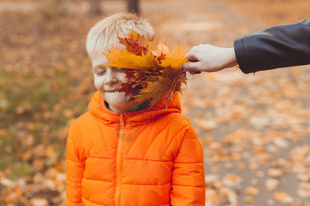 秋公园橙色夹克的快乐儿童男孩肖像 秋天秋季季节和儿童概念图片