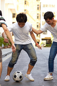 玩放学后游戏 在街上踢足球的三个年青的亚裔男孩图片