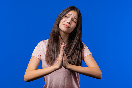 年轻女子祈祷 请求向她道歉 她有罪 蓝色背景 充满希望的祈祷女孩要求有人满足她的欲望 帮助信徒成人饶恕感激感恩文化上帝信仰祷告情图片