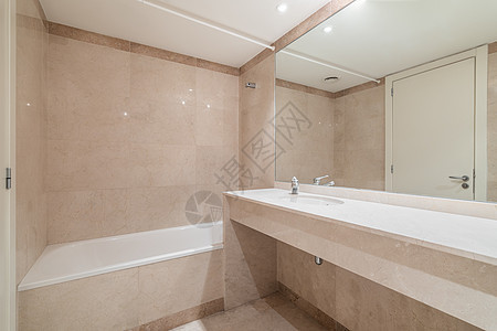 用于沐浴和日常淋浴的大型白色干净浴缸 带全身镜的墙壁和现代浴室的大理石台面洗脸盆 采用时尚的米色瓷砖装饰图片