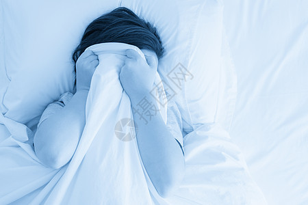 悲伤的女人躺在被毯子盖满的浴缸里 她脸上有毛毯苏醒女孩女性枕头头发闲暇寝具时间卧室黑发图片