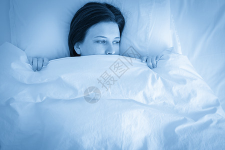 年轻不高兴的女士躺在床上 蓝调的肖像图片