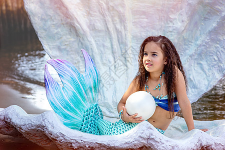 一个穿美人鱼服装的漂亮小女孩 坐在一个大海壳里 大珍珠图片