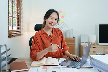 一位女企业主的画像 她在工作中使用电脑和财务预算文件成功地投资了她的企业时 脸上挂着快乐的笑脸商务摄影会议员工手臂衬衫幸福簿记经图片