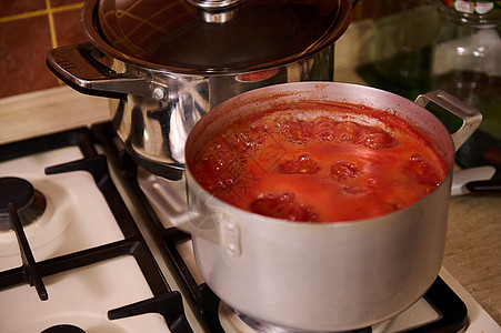 根据意大利传统食谱制成的切口番茄汁 在炉灶上的金属酱锅里沸腾图片