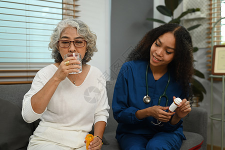 医生或护士向老年妇女展示处方药瓶 居家保健服务理念图片