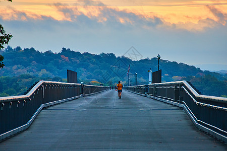 清晨光照亮长直水泥桥上的慢跑者图片