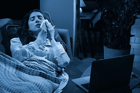 坐在沙发上的年轻女性 身上盖着一条毯子 冻得鼻涕直流 发烧 被抓 生病的女孩有流感症状 流感或病毒概念客厅疾病调子鼻子女士健康喷图片