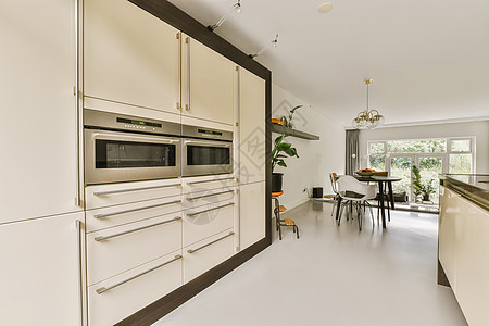 一个有白柜子和餐桌的厨房用餐内阁微波柜台风格烤箱财产公寓木头窗户图片