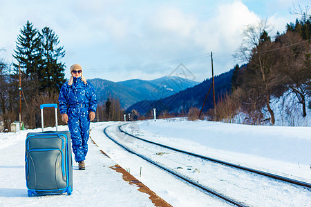 穿着滑雪服的妇女站在铁路附近食物购物场景生活运输城市旅行金发女郎乘客平台图片
