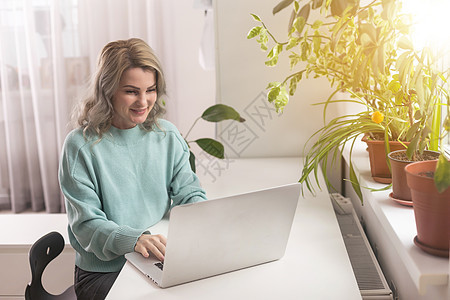 年轻自信有趣的成功员工女商务人士穿着休闲蓝色衬衫 在工作场所的白色办公桌上工作 笔记本电脑在轻便的现代办公室室内浏览成就职业理念图片