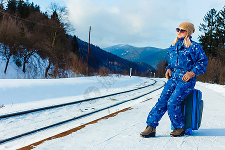 穿着滑雪服的妇女站在铁路附近场景女士运输城市食物平台女性商业生活游客图片