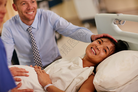 这都值得 一位年轻女性躺在医院里 与她丈夫在背景中图片
