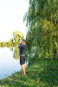 钓鱼里尔 那家伙在湖面上扔了根钓鱼棒 放松和灵魂爱好的概念 (笑声)图片