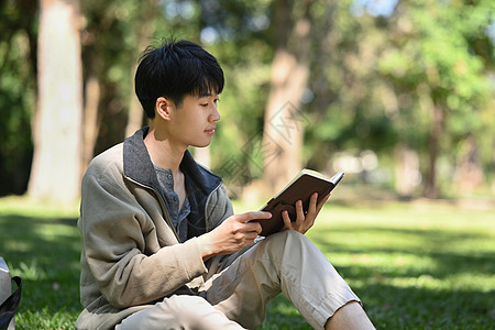 安静的大学生阅读书籍 在校园草坪上放松 教育和生活方式概念图片