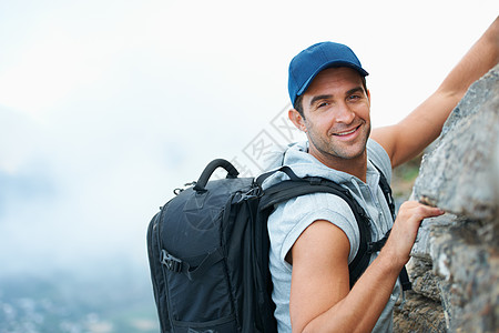 年轻登山者在摄影机上微笑 他正在攀升悬崖的顶部 (笑声)图片