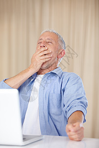 工作到很晚 一个成熟的男人在笔记本电脑上打哈欠图片