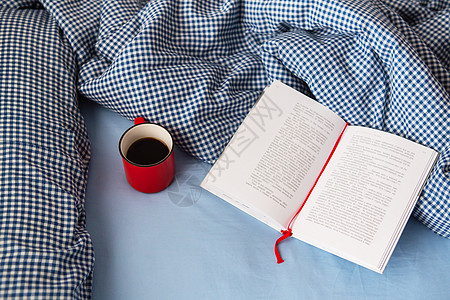 乌克兰 罗夫诺 — 2021 年 8 月 11 日 在寒冷的冬日 床上铺着一条舒适的毯子 一本打开的书和一杯热红咖啡的顶视图 放图片