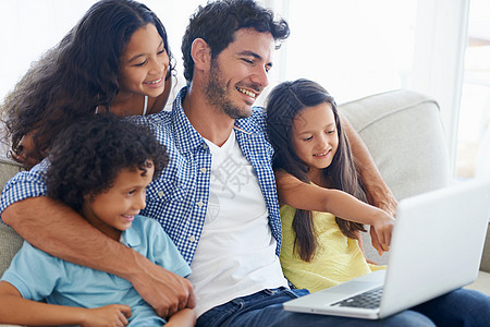 一个坐在沙发上 使用笔记本电脑的笑容家庭图片