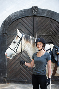 一位年轻女子站在外边 带着马匹全副武装的骑马装备图片