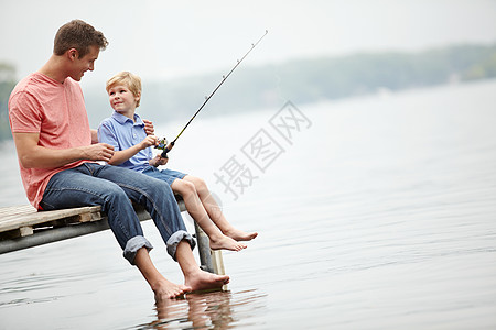 坐着钓鱼的孩子优质的父子时光 一位父亲坐在河边的窗台上教他的儿子如何钓鱼背景