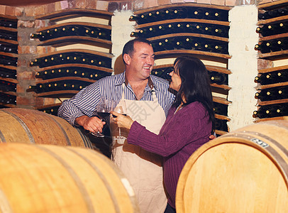 他们一起做漂亮的葡萄酒 一个成熟的红酒师 和他妻子在酒窖里烤面包图片