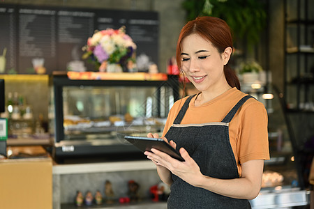 美丽的亚洲女性小企业主使用数字平板电脑 站在室内咖啡馆里 创业精神 创业理念图片