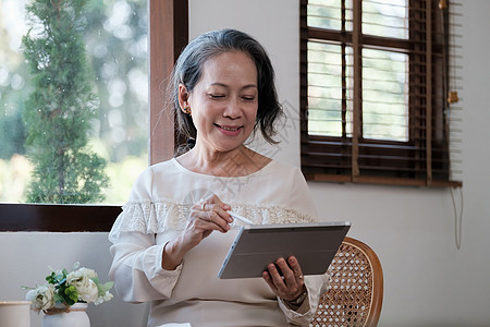 使用平板 电子学习 在家庭办公室远程在线工作的首席校长教师CEO 主导教师 在互联网上工作经理人士退休女士互联网女性老年技术桌子图片