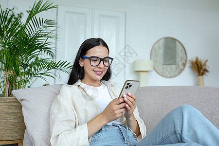 一个年轻少女在家睡沙发上 用电话打电话 接收信息 与朋友聊天以及博客青少年房间命令约会房子阅读购物享受民众图片