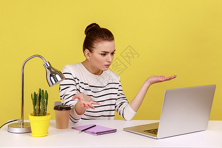 妇女用笔记本电脑坐在工作场所 看笔记本电脑屏幕时表现出愤怒和愤慨的表情图片