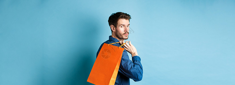 站在蓝色背景上 快乐男人背着购物 向后看的后视图商业成人促销广告生活购物者店铺成功胡子工作室图片