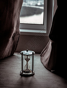 银色沙漏或沙玻璃放在房间的玻璃窗上倒数时间小时窗帘窗户手表滴漏工具家具生活图片