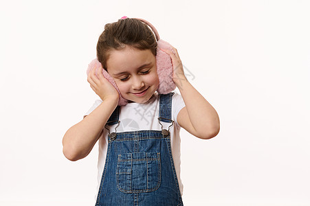 时髦的小女孩握着手在耳膜上 享受她的新冬季配饰 保护你的耳朵免受寒冷图片