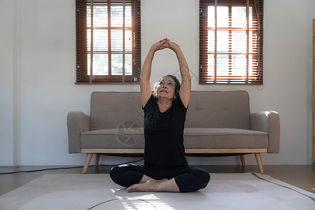 60多岁身着运动服的退休亚洲妇女在起居室练瑜伽 健康快乐成人娱乐老年训练平衡女士健身房运动体操活动图片