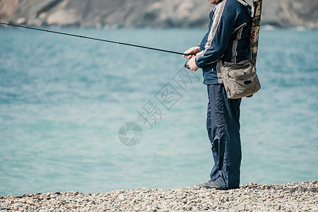 海上钓鱼的人爱好收紧鱼夏季的钓鱼线卷轴 平静的海面 渔夫的特写镜头用手在鱼竿上扭动渔线轮 在户外海里钓鱼 慢动作行动纺纱支撑活动图片