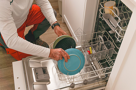 男人把盘子放在洗碗机上弯曲厨房公寓推杆倾斜台面清洁家庭家务白色图片
