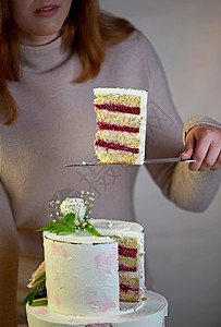 女孩切开并端上一块蛋糕 灰色背景中用鲜花装饰的喜庆婚礼两层蛋糕粉色美食绿色风格玫瑰生日花朵派对甜点庆典图片