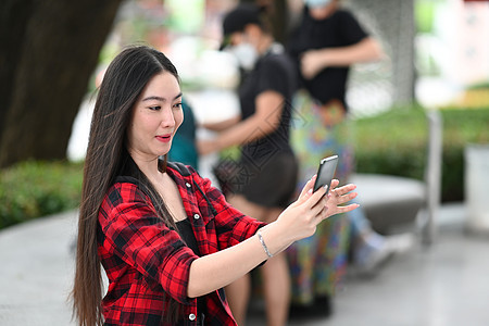 年轻亚裔女性使用智能手机 持有信用卡在网上买东西旅游日落幸福照片享受摄影师自拍吸引力成人游客图片