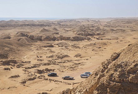 四辆汽车停在沙漠里 地平线上的海面图片