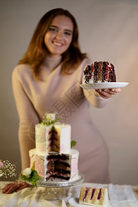 女孩切开并端上一块蛋糕 灰色背景中用鲜花装饰的喜庆婚礼两层蛋糕庆典花朵绿色白色甜点派对生日风格粉色奶油图片