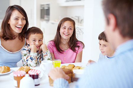欢声笑语围绕着令人垂涎的早餐 一个幸福的家庭在早餐时间一起坐在厨房的桌子旁图片