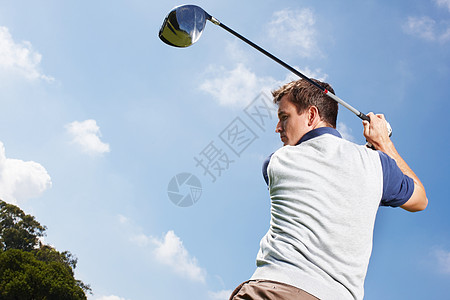 真是高尔夫球专家 年轻人在蓝天对着一局高尔夫球赛中全速挥舞图片