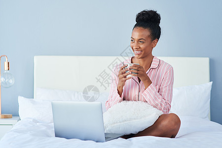 床上电脑今早我感觉很放松 一个迷人的年轻女人 在家床上喝早间咖啡 享受着清晨的咖啡背景