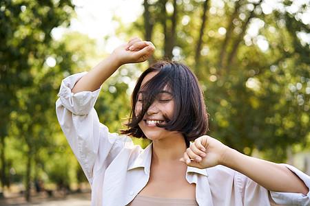 人们的生活方式 年轻黑发女人的肖像 她跳舞 微笑和笑着 手举高地在公园中走路 享受外面的夏日自由快乐喜悦福利治疗假期女性女孩学生背景图片