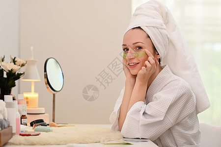 浴袍中的大肠女性在眼下施以抗疲劳症的外表 其美容治疗和自我护理概念图片
