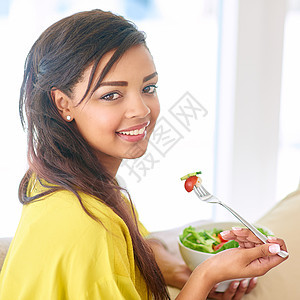 保持健康一面 一个年轻女人在家里吃沙拉图片