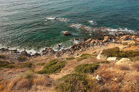 从用草 岩石和深蓝色海水盖的陡峭的海岸小山的看法在背景中 北塞浦路斯卡尔帕斯图片