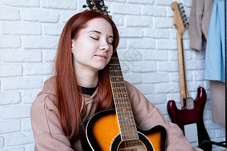 在家里弹吉他的年轻女子乐器女性艺术家砖墙吉他手头发音乐家成人爱好幸福图片